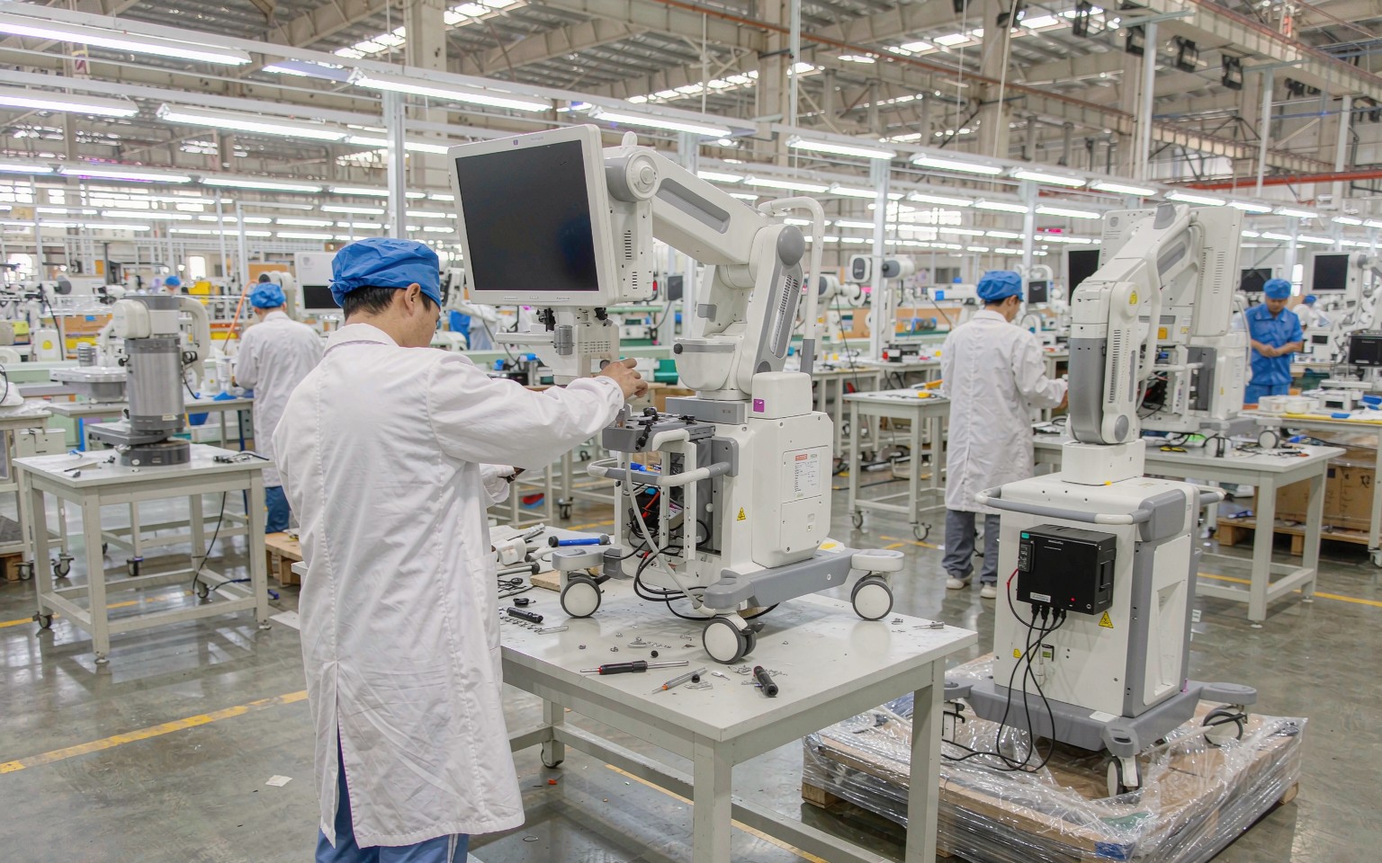 Engineers assembling a mobile C-arm X-ray imaging system in an assembly hall
