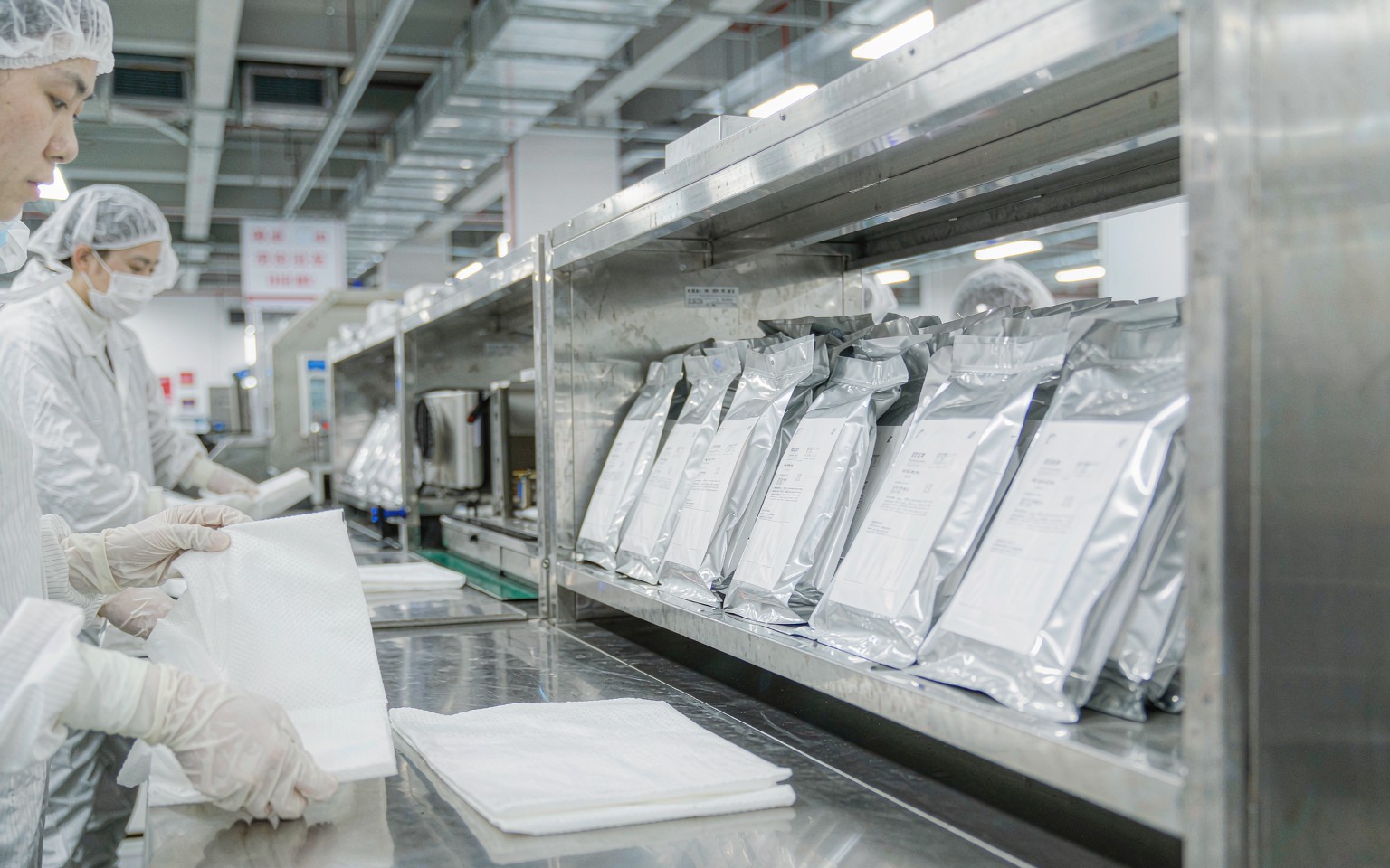 Sterile surgical drapes being folded and packed on a cleanroom line